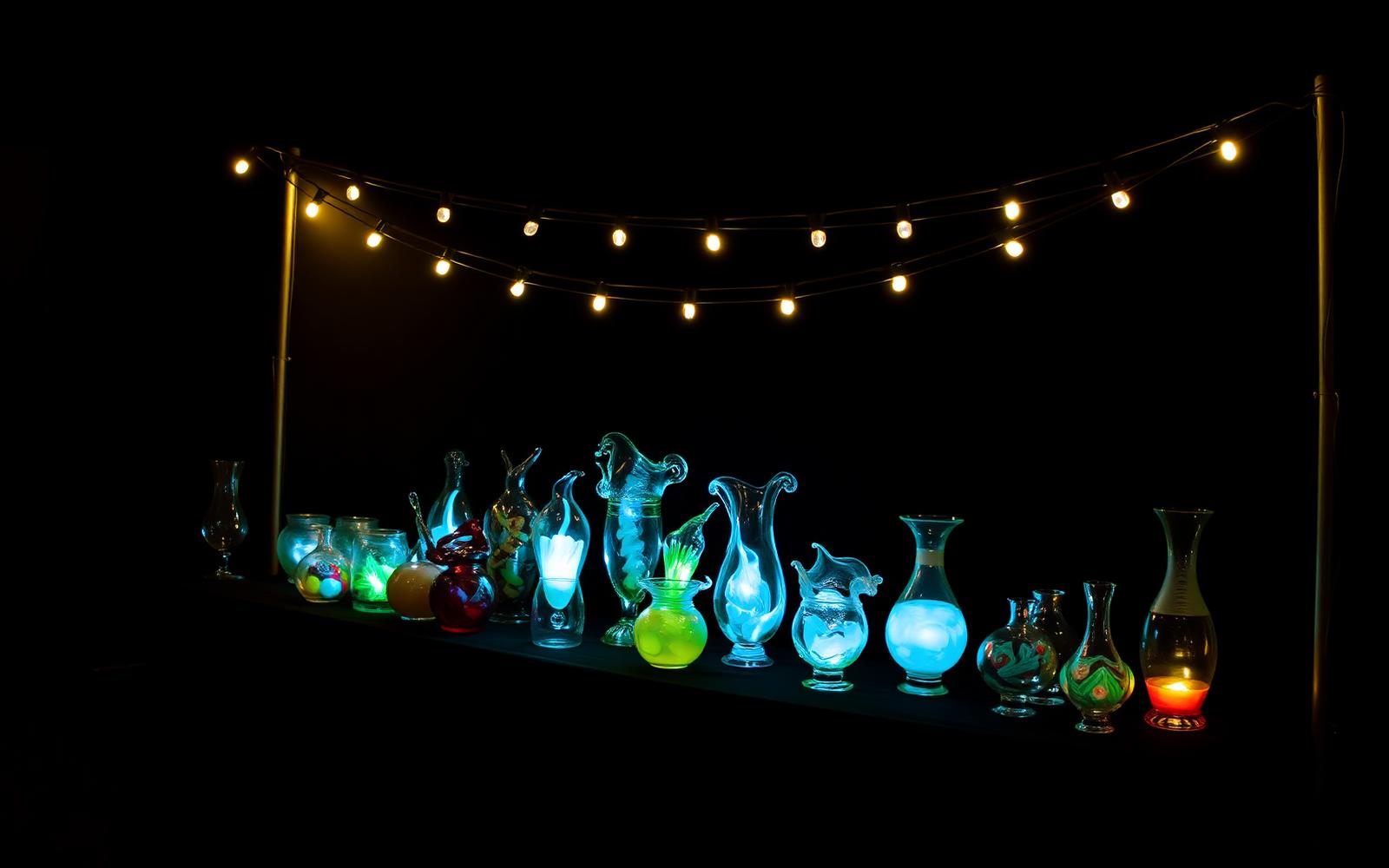 Lit market table of handmade glass pieces at night